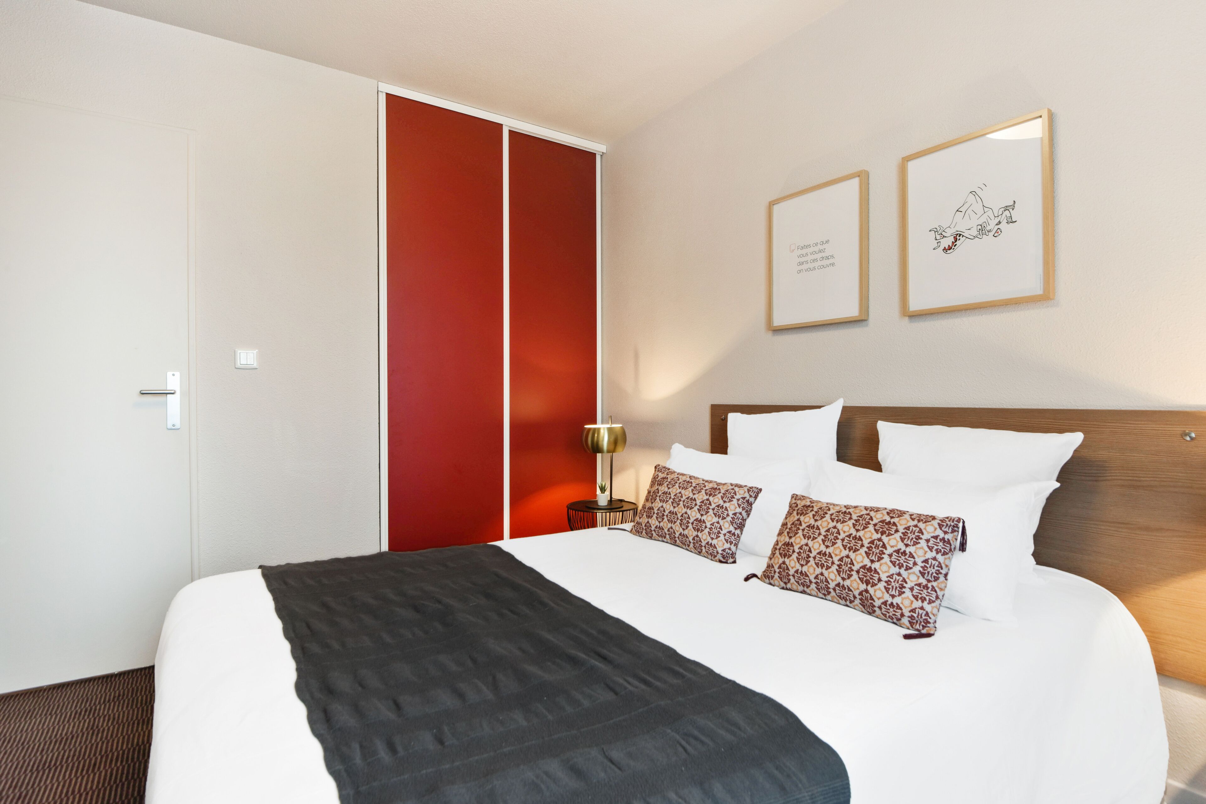 Una habitación de hotel con una cama grande, un armario y dos cuadros en la pared.
