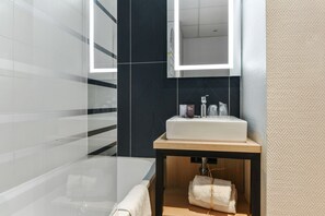 Une salle de bain moderne avec une douche à parois de verre, un lavabo blanc avec un miroir au-dessus et un meuble-lavabo en bois.