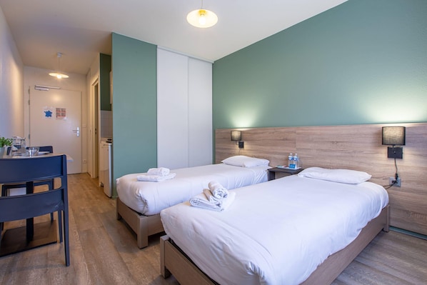 A hotel room with two beds, a desk, and a chair. - Comfort Aparthotel Le Mans (Le Mans)