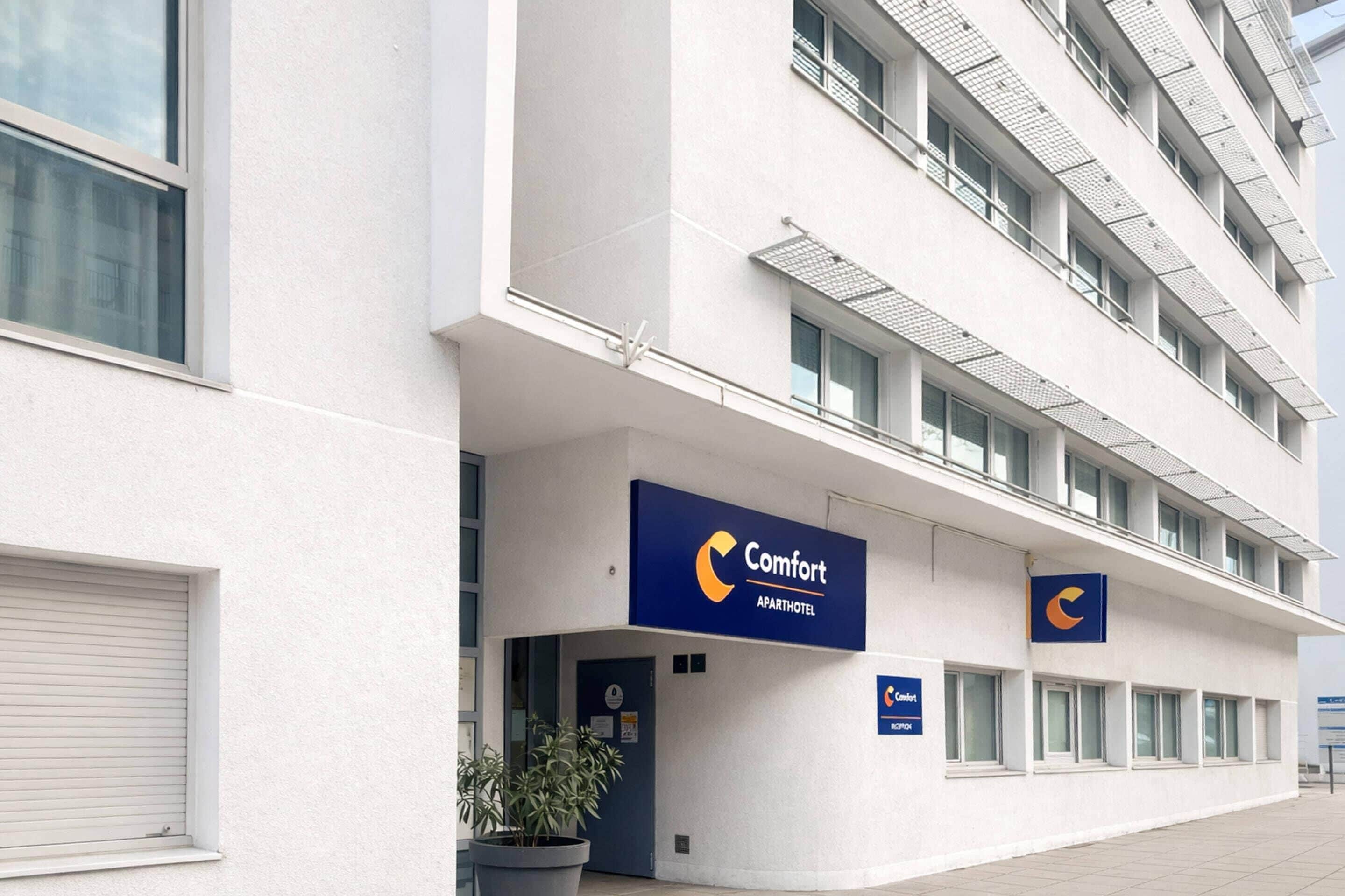 En moderne bygning med et skilt, der viser 'Comfort Apart Hotel'.