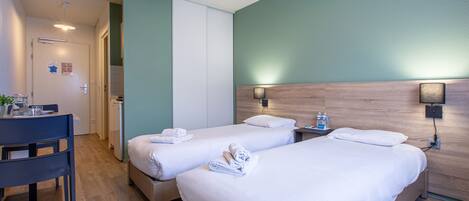 A hotel room with two beds, a desk, and a chair.
