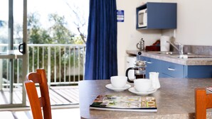 Un comedor con una mesa preparada para dos personas, una cafetera y una revista.