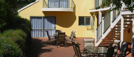 Ein Gebäude mit gelbem Giebel, einem Balkon und einer Außenbereich-Sitzgelegenheit mit Stühlen und Tischen.