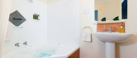 A bathroom with a bathtub, a sink, and a mirror.