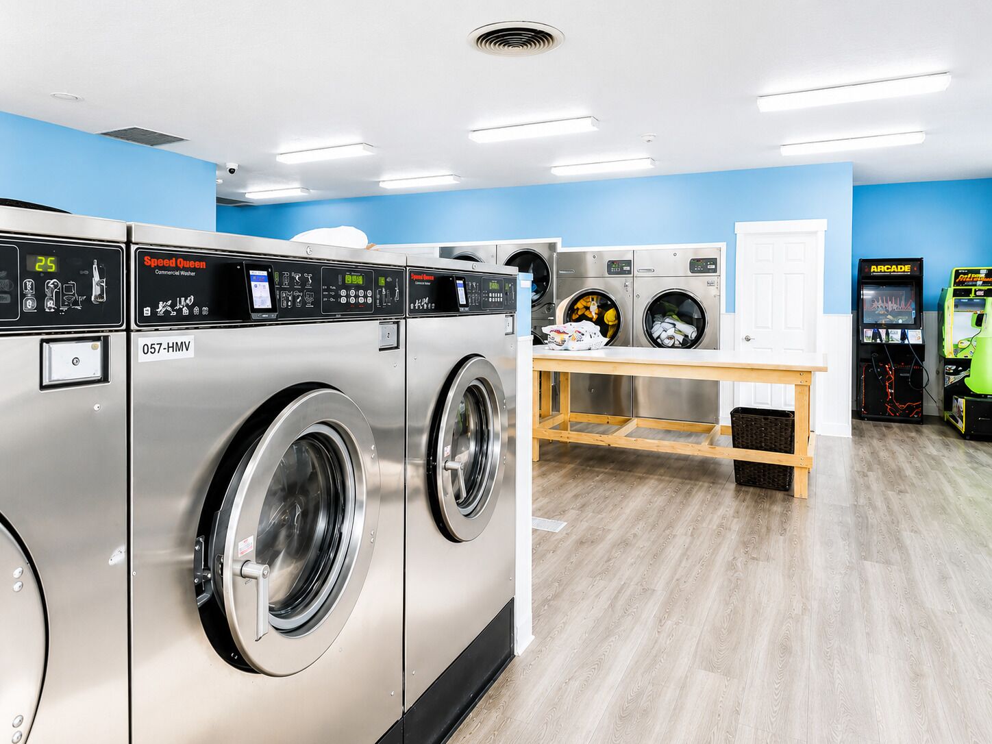 A laundromat with multiple washing machines, a dryer, and arcade games.