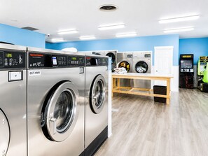 A laundromat with multiple washing machines, a dryer, and arcade games.