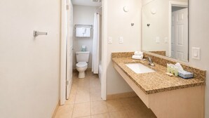 A bathroom with a sink, mirror, and toilet. - Heber Inn  (Heber City)