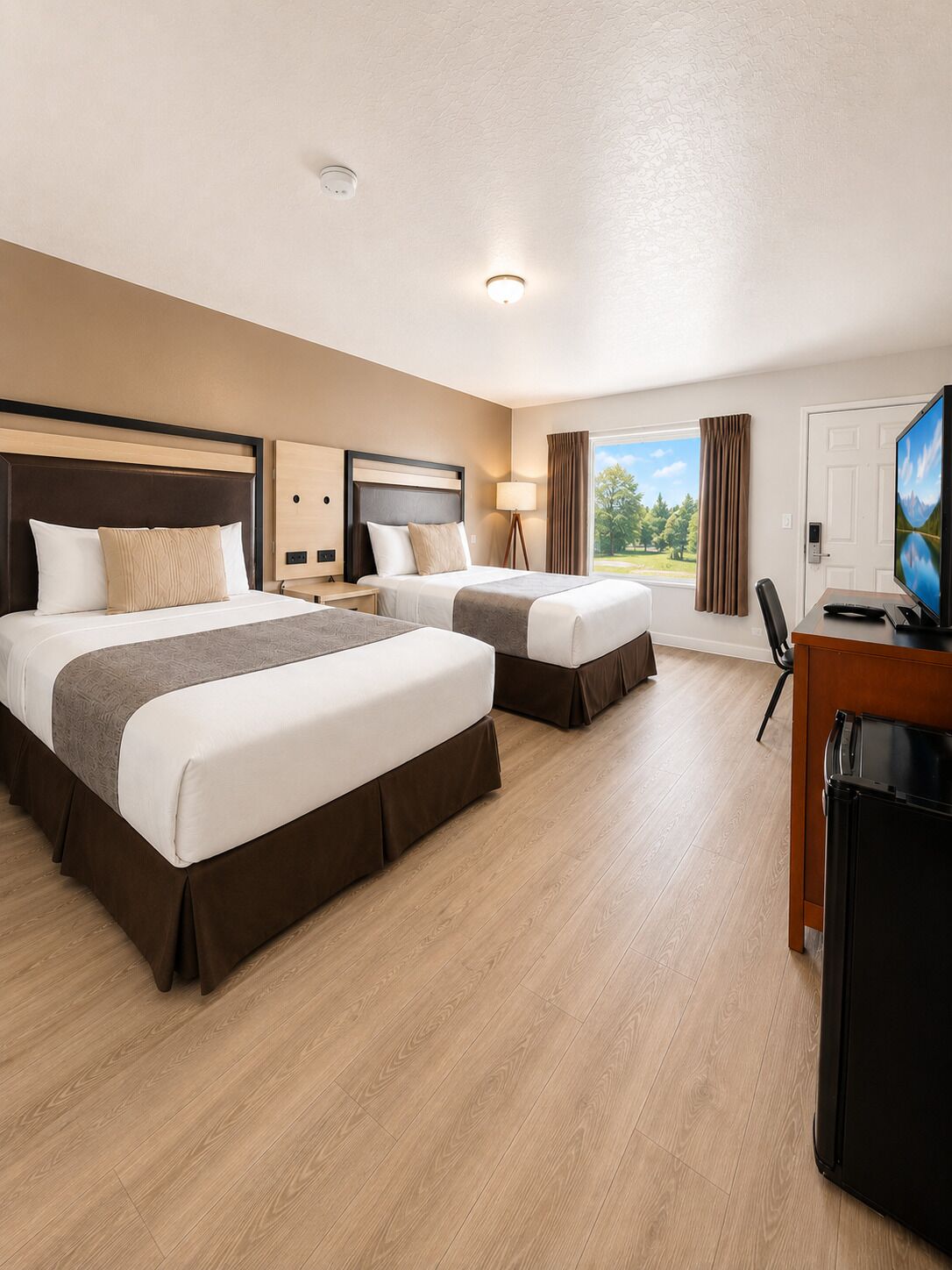Habitación de hotel con dos camas, un escritorio, un televisor y una ventana con cortinas.
