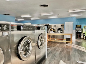 A laundromat with multiple washing machines and dryers, a wooden table, and a blue wall. - Heber Inn  (Heber City)