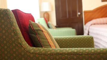 A room with a green patterned sofa, a red pillow, and a wooden door in the background.
