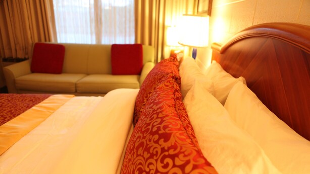 A hotel room with a bed, a sofa, and a lamp. - Arcadia Hotel (Gering)