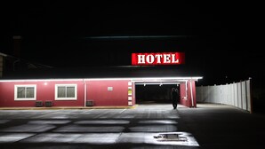 A hotel with a prominent "HOTEL" sign, a red exterior, and a covered entrance. - Arcadia Hotel (Gering)