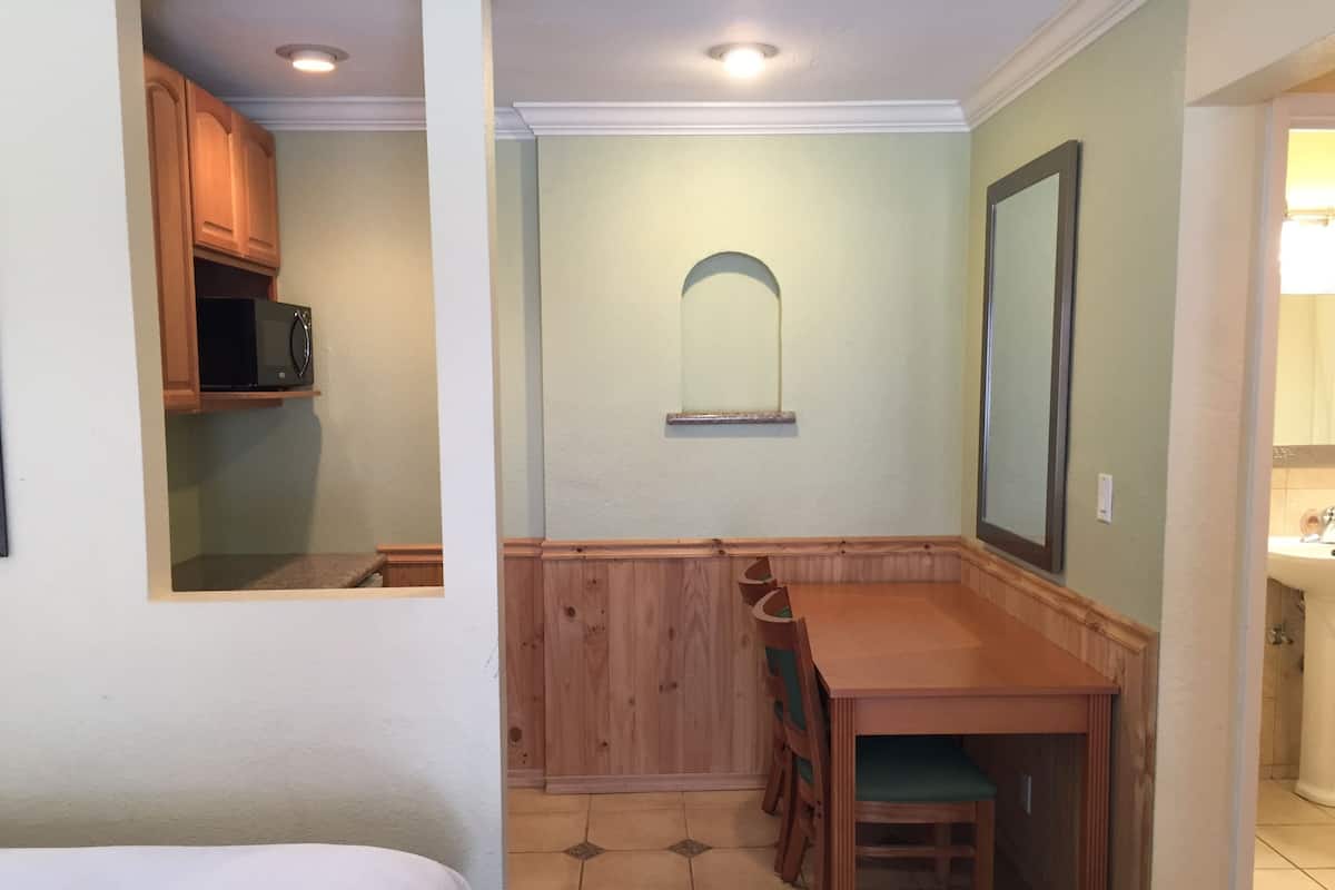 A compact kitchen with a dining area, wooden cabinets, and a microwave.
