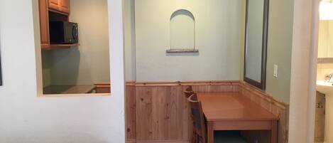 Cocina compacta con comedor, armarios de madera y microondas.
