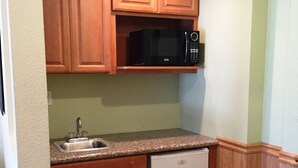 A compact kitchen with wooden cabinets, a microwave, a dishwasher, and a sink.