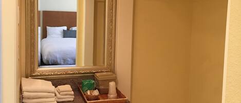 A hotel bathroom with a mirror, a towel rack, and a small tray with toiletries.
