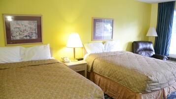A hotel room with two beds, a nightstand with a lamp, a telephone, and two framed pictures on the wall.