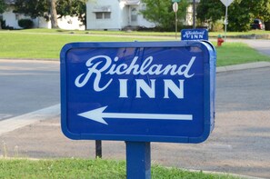 Uma placa azul com o texto "Richland INN" e uma seta apontando para a esquerda.