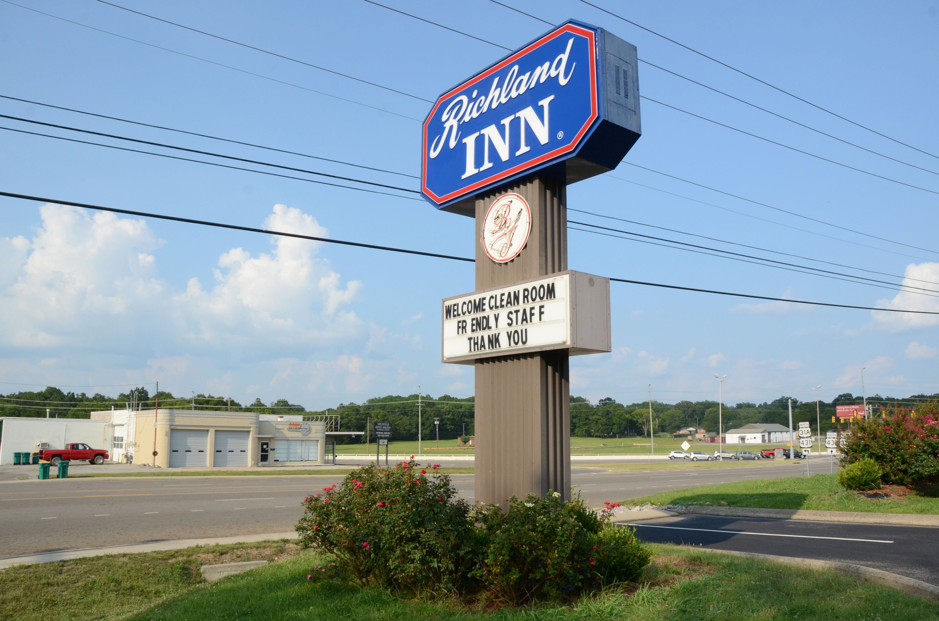 Señal de Richland Inn con un reloj y un mensaje de bienvenida.