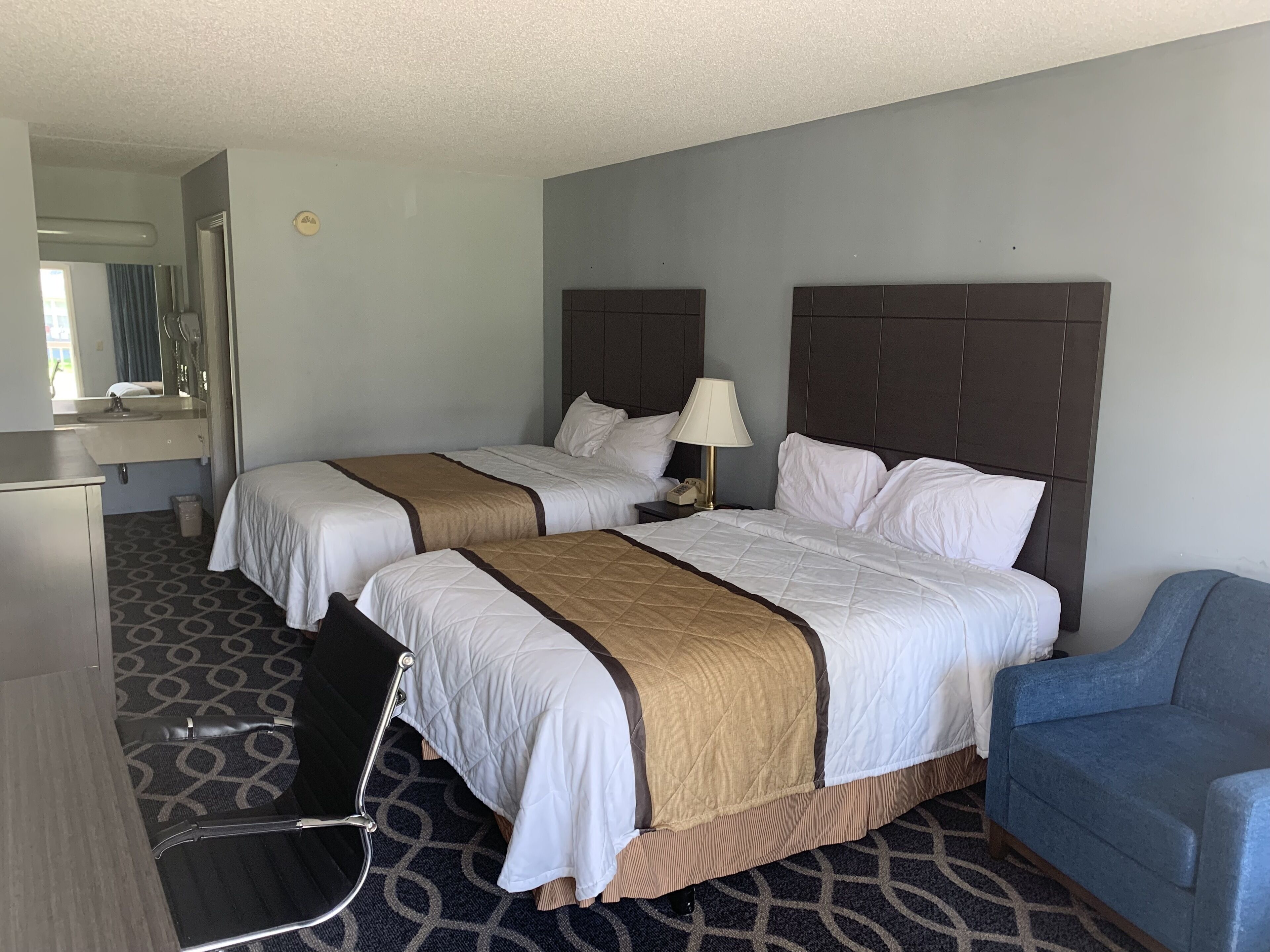 Une chambre d’hôtel avec deux lits, un bureau, une chaise et une salle de bain.