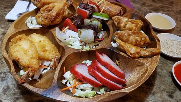 A wooden platter with various fried foods, including chicken wings, fish, and vegetables. - Merrill Field Inn (Anchorage)