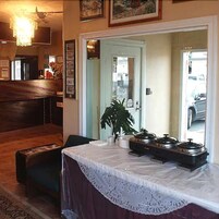 Una habitación con un banco de madera, una mesa con mantel de encaje y una planta.