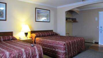 Una habitació d'hotel amb dos llits, una tauleta de nit amb una làmpada, un quadre amb marc a la paret i una porta que condueix a un bany.