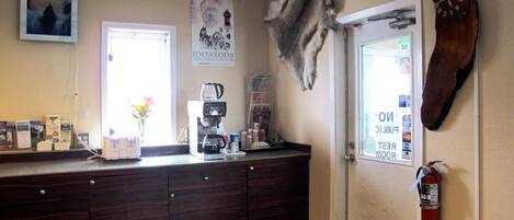 A kitchen with a coffee maker, a clock, and a fire extinguisher.