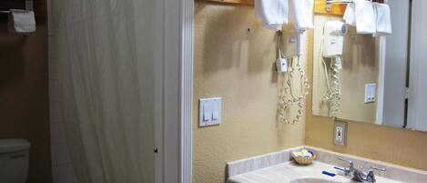 A bathroom with a shower curtain, a toilet, a sink with a mirror, and a towel rack.