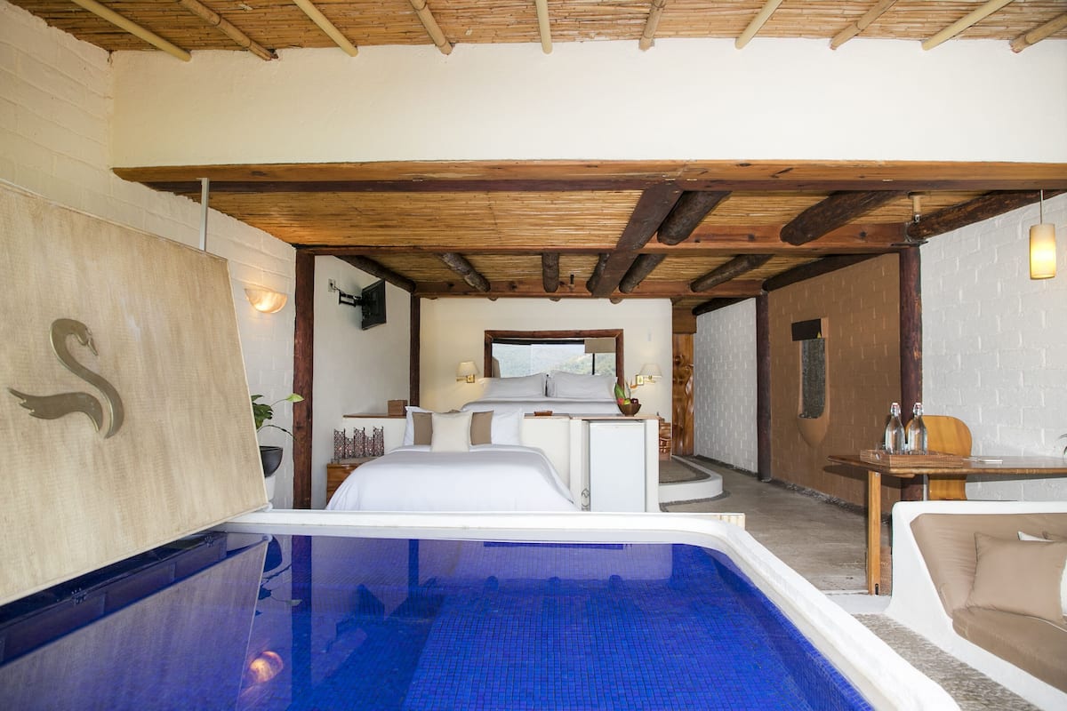 Ein Zimmer mit Pool, Bett, Tisch und Blick ins Freie.