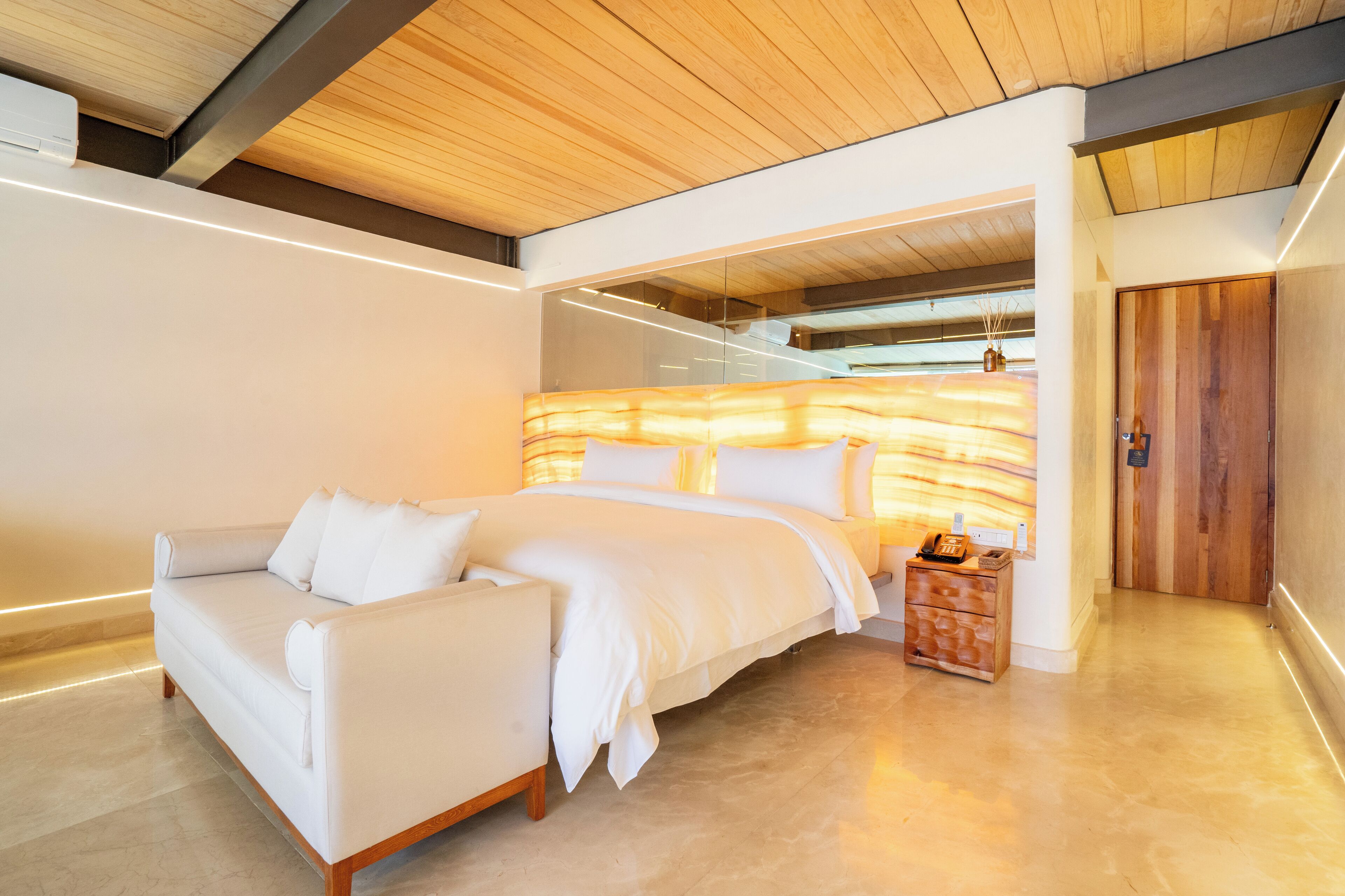 Un dormitorio moderno con una cama grande, un sofá blanco y una puerta de madera.