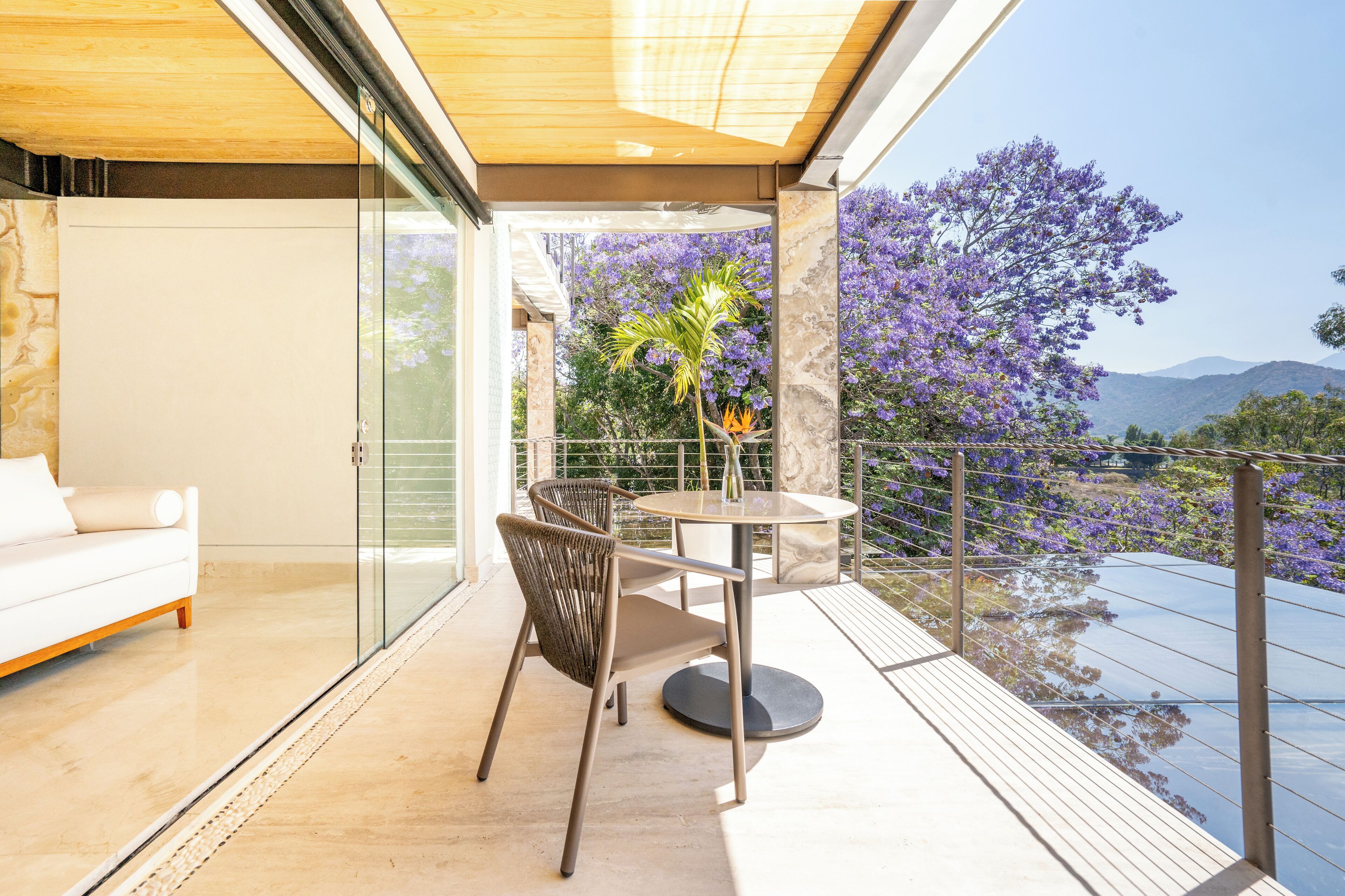 A modern balcony with a glass door, a round table, and a white sofa.