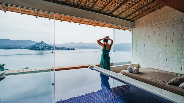 A room with a glass infinity pool, a view of a lake, and a wooden ceiling. - El Santuario Resort & Spa (Valle de Bravo)