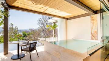 A modern outdoor pool area with a glass enclosure, a wooden ceiling, and a view of the surrounding landscape.