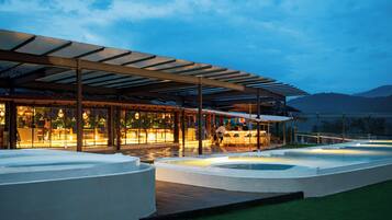 A modern outdoor pool area with a covered seating area and a bar.