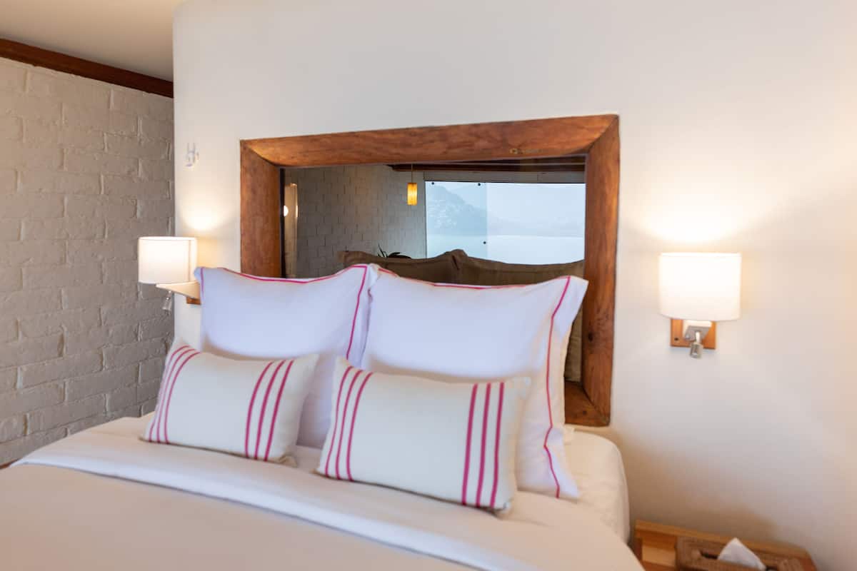 Ein Hotelzimmer mit einem großen Bett, zwei Nachttischlampen, einem Holzkopfschild und einer Ziegelwand.