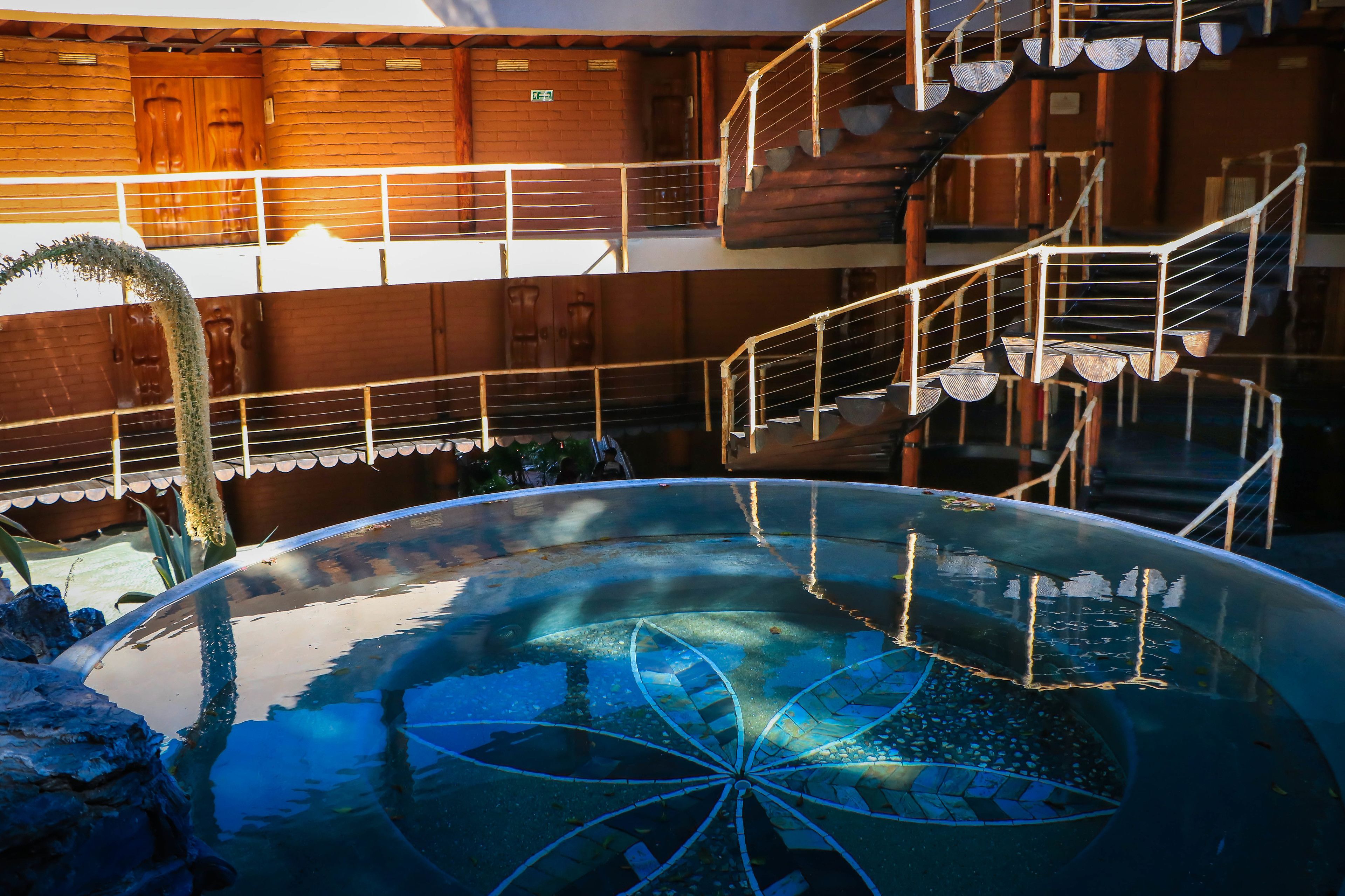 A multi-level hotel with a glass-bottomed pool, wooden walls, and a spiral staircase.