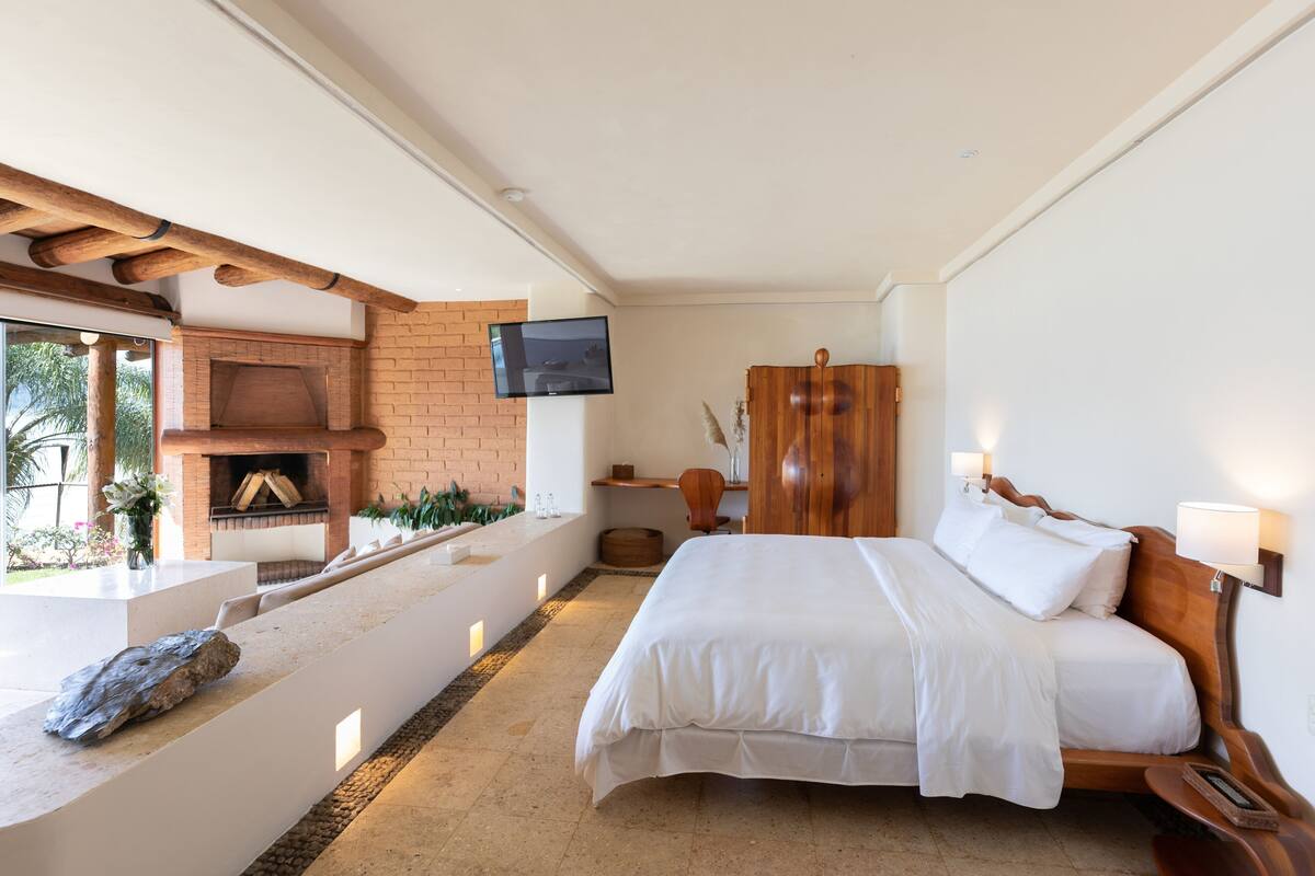 Ein Schlafzimmer mit einem Bett, einem Fernseher, einem Kamin aus Ziegelsteinen und einer Steinsitzbank.