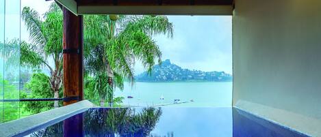 A view from a balcony with a glass floor, overlooking a calm body of water and a distant island.