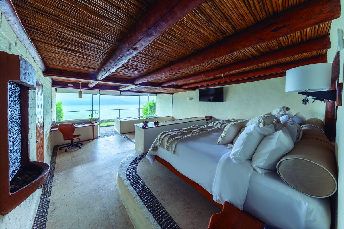 Ein Zimmer mit einem Bett, einem Schreibtisch und einem Stuhl. Ein Fenster bietet Blick ins Freie.