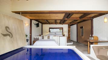 Una habitación con una piscina grande, una cama, una mesa de comedor y vistas al exterior.