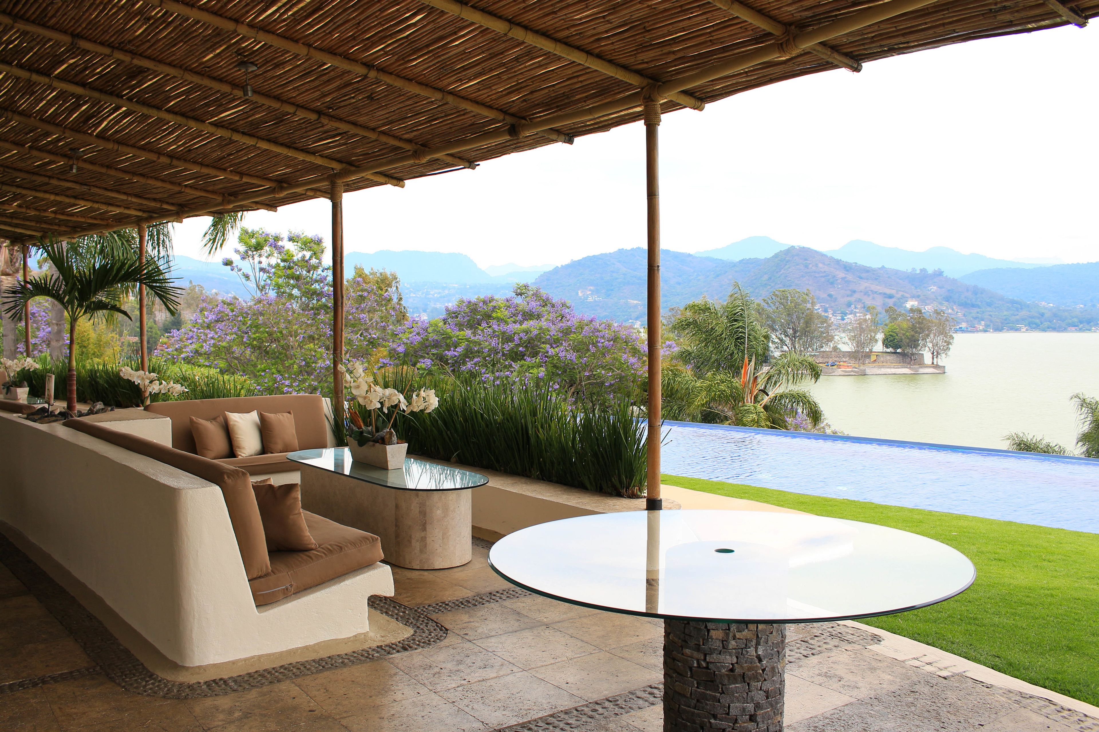 A covered outdoor seating area with a view of a lake and mountains.