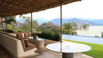A covered outdoor seating area with a view of a lake and mountains.