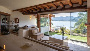 A spacious living area with a large window overlooking a lake, a wooden ceiling, and a modern sofa. - El Santuario Resort & Spa (Valle de Bravo)