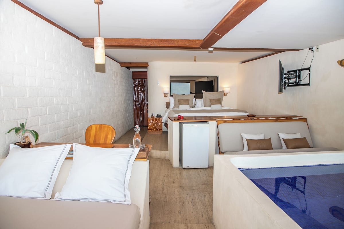 Ein kleines Hotelzimmer mit Bett, Schreibtisch, Stuhl, Fernseher und Minikühlschrank.