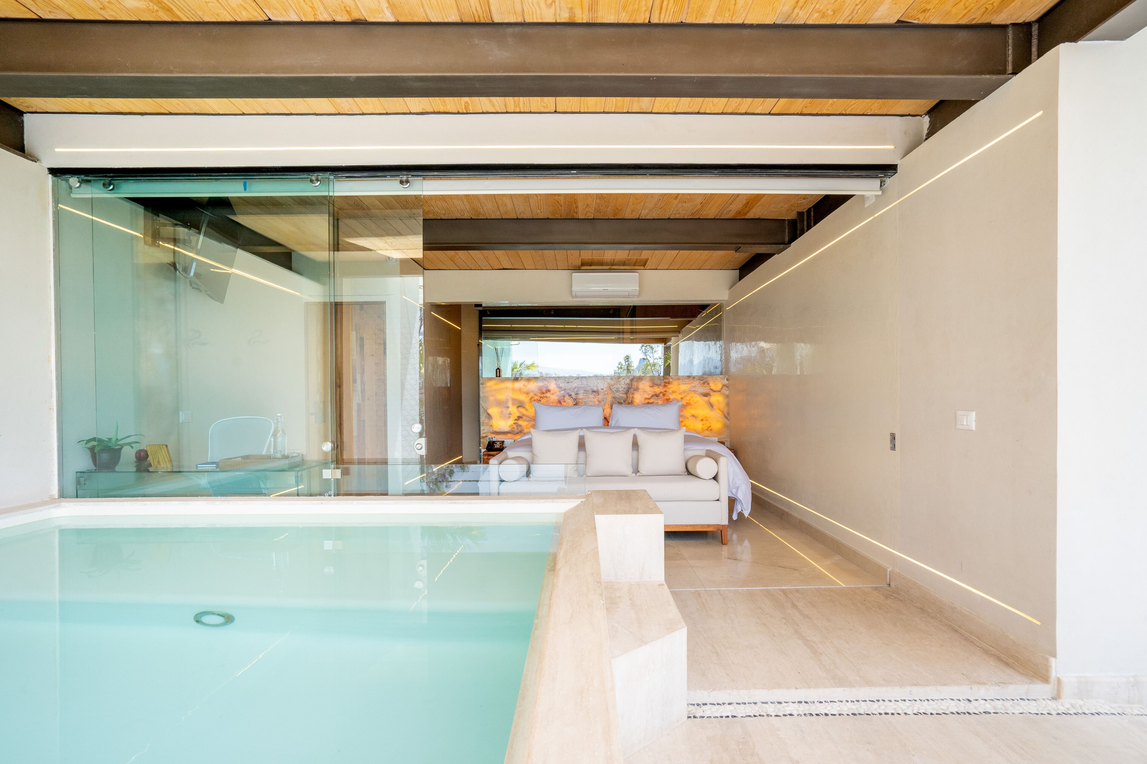 A modern interior with a glass-enclosed pool, a sofa, and a decorative wall.