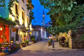A cobblestone street lined with buildings, a mosque with a minaret, and a parked motorcycle. - Zeynep Sultan Hotel (Istanbul)