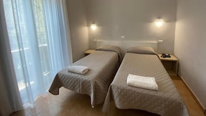 Una habitación de hotel con dos camas, una ventana con cortinas translúcidas y lámparas de noche.