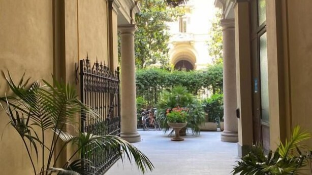 Un pasillo con columnas, plantas en macetas y vista a un jardín.