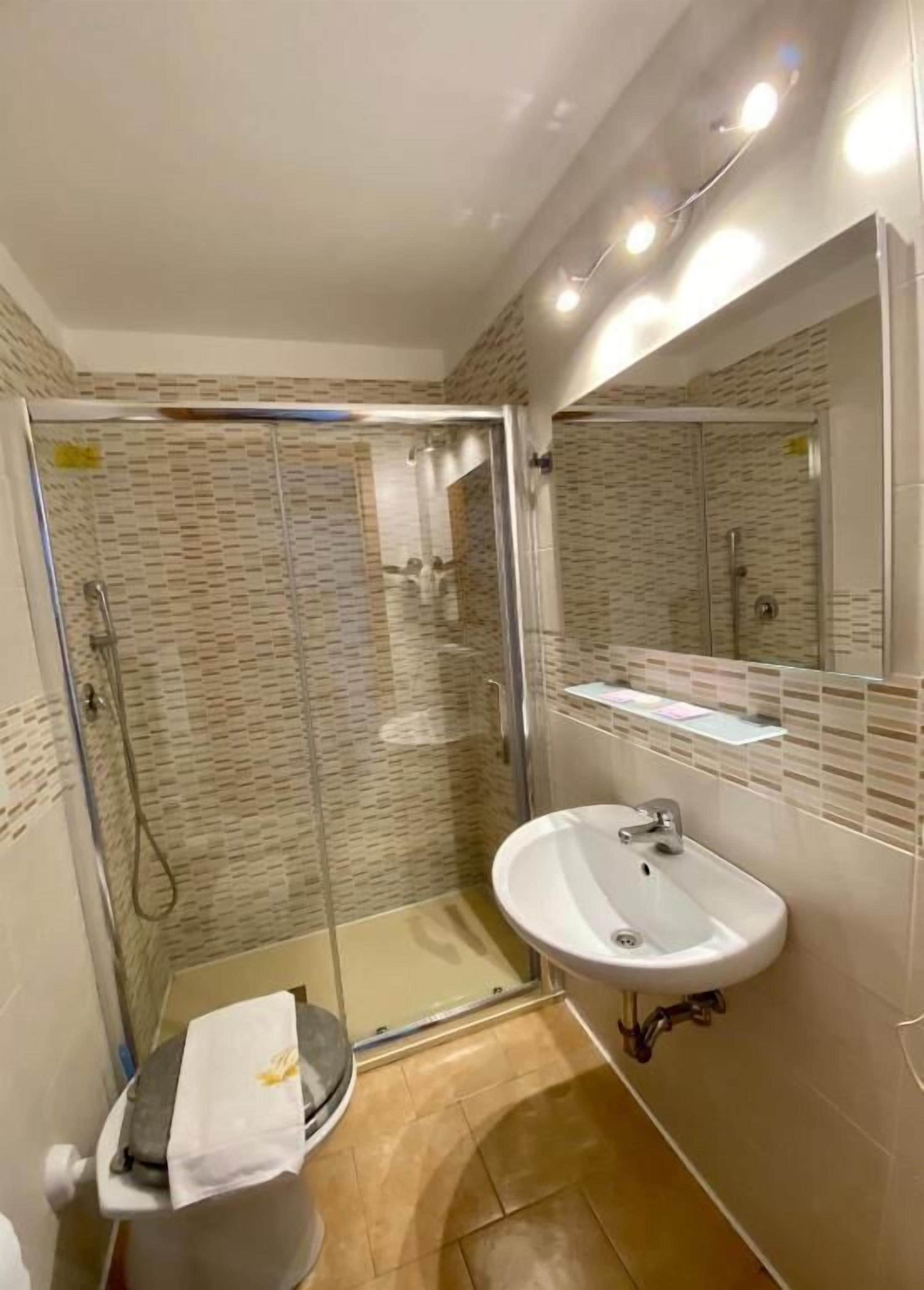 A bathroom with a glass-enclosed shower, a sink, and a toilet.